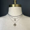 Three necklaces styled to show how to wear them. Two pendants and one beaded necklace.